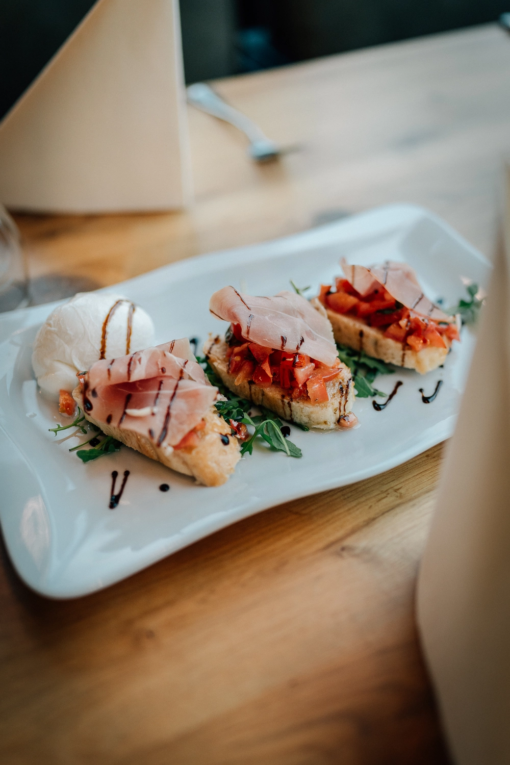 Sinn Kitchen – Restaurant – Ein Koch bereitet Bruschetta mit Prosciutto und Mozzarella zu.