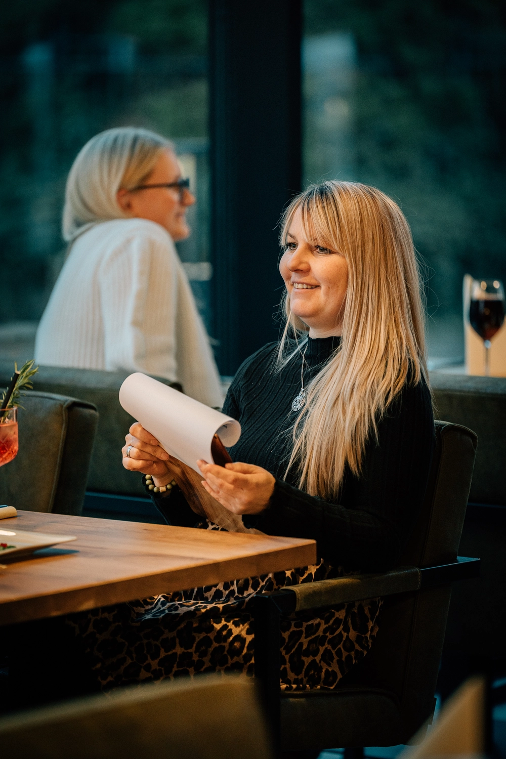 Sinn Kitchen – Restaurant – Vier junge Leute genießen ein geselliges Beisammensein in einem Restaurant oder Café am Abend. Sinn Kitchen - Restaurant -