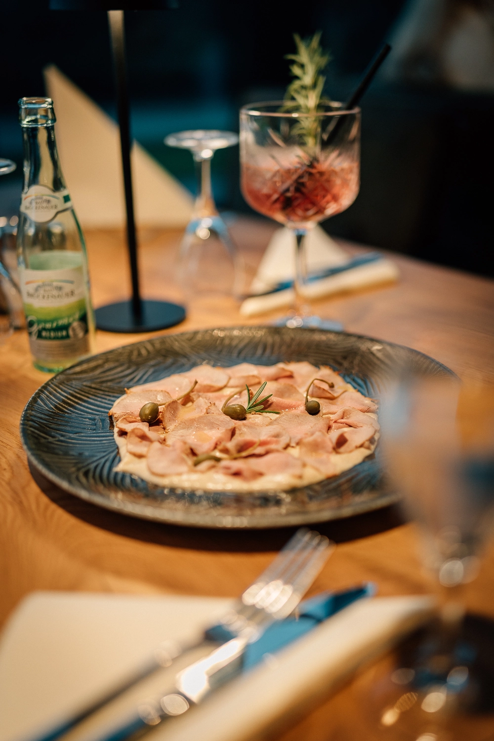 Sinn Kitchen – Restaurant – ein gedeckter Tisch mit einem Teller Essen und einem Cocktail.