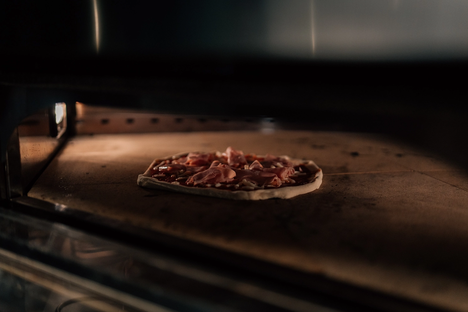 Sinn Kitchen – Restaurant – Eine Pizza wird in einem gewerblichen oder speziellen Pizzaofen gebacken.