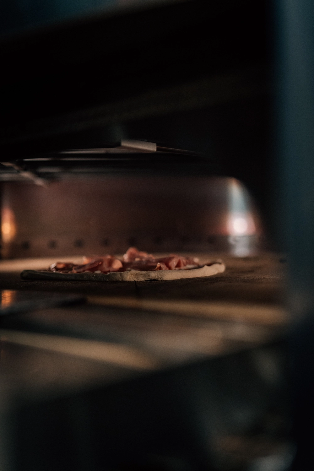 Sinn Kitchen – Restaurant – Eine Pizza wird in einem gewerblichen oder speziellen Pizzaofen gebacken.