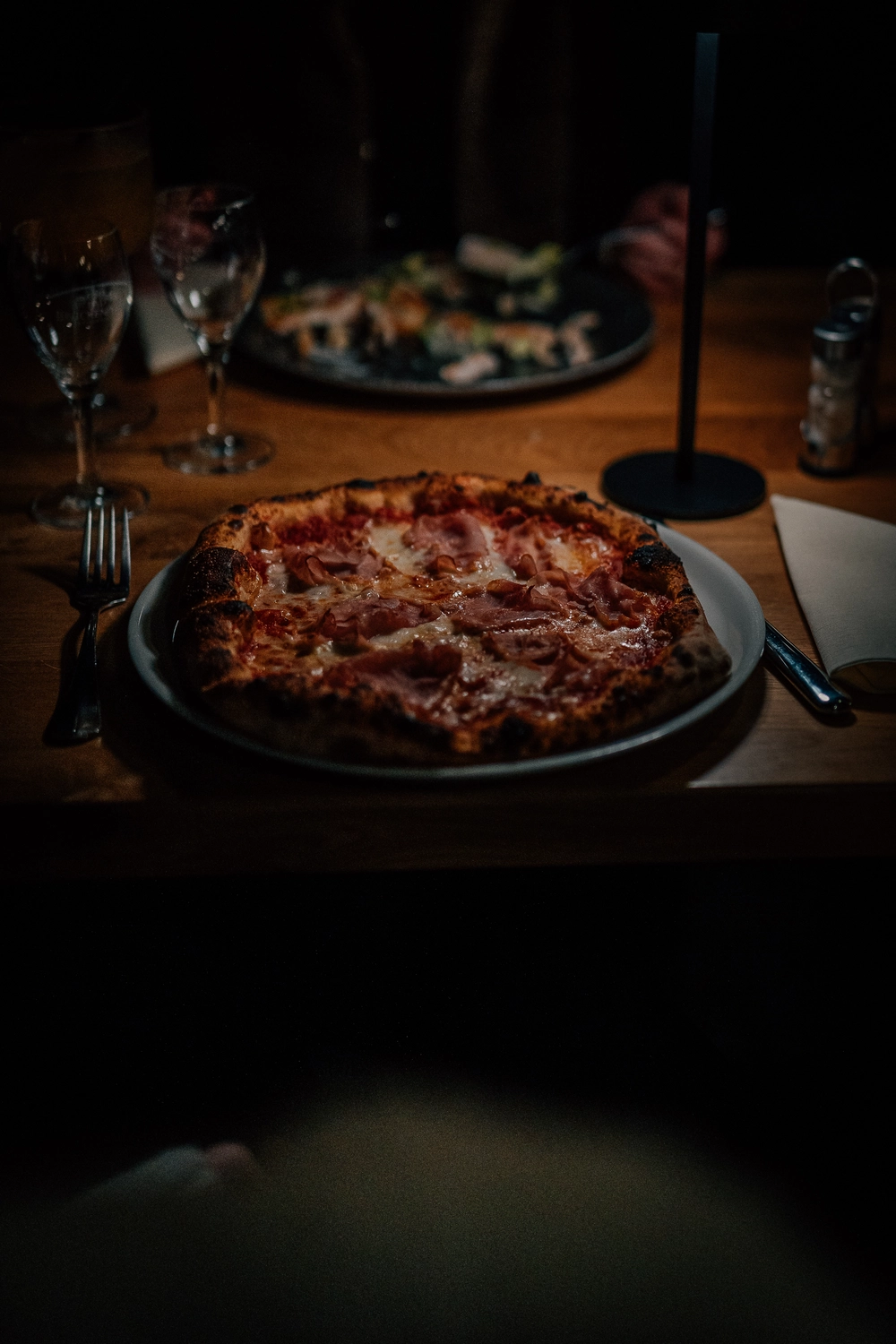 Sinn Kitchen – Restaurant – Eine frisch gebackene Pizza wird mit einem Pizzaschieber aus dem Ofen genommen.